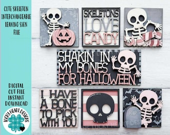 May include: A collection of Halloween-themed wooden signs featuring skeleton designs. The signs include phrases like "Skeletons Love Candy" and "Shakin' in My Bones for Halloween." The color palette includes black, white, and pink.