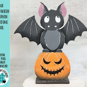 May include: A Halloween-themed decoration featuring a cartoon bat perched atop an orange jack-o'-lantern. The bat is black with gray accents and pink ears. The pumpkin has a carved face. Text on the left reads "BAT HALLOWEEN PUMPKIN STANDING FILE".