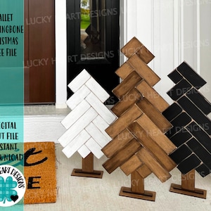Könnte beinhalten: Drei hölzerne Weihnachtsbaum-Dekorationen in Form eines Fischgrätenmusters. Die Bäume sind in Weiß, Braun und Schwarz lackiert. Die Bäume stehen auf einem Holzsockel. Der Text "PALLET HERRINGBONE CHRISTMAS TREE FILE" ist im Bild sichtbar.