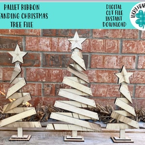 May include: Three wooden Christmas trees made from pallet wood with a star on top. The trees are standing on a brick wall background. The text "PALLET RIBBON STANDING CHRISTMAS TREE FILE" is at the top of the image. The text "DIGITAL CUT FILE INSTANT DOWNLOAD" is at the top right of the image.