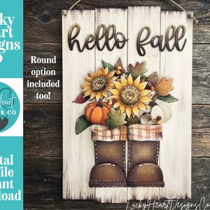 May include: A rectangular white wooden sign with the text hello fall in dark script. The sign features a layered cutout design of two brown boots filled with sunflowers, orange and white pumpkins, and autumn leaves on a rustic plank background.