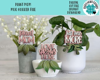 May include: A collection of decorative plant stakes with phrases like "Plant Mom," "Just One More," and "Love Grows Here." The stakes are in front of potted plants and flowers. The image also includes the text "Digital Cut File Instant Download."