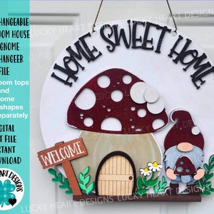 Op de afbeelding: Een ronde houten deurhanger met de woorden "HOME SWEET HOME" in het zwart. Het heeft een paddenstoelenhuis met een rood en witte paddenstoelenkap, een kabouter en het woord "WELCOME" op een bord. De tekst "INTERCHANGEABLE MUSHROOM HOUSE AND GNOME DOORHANGER FILE" is ook aanwezig.