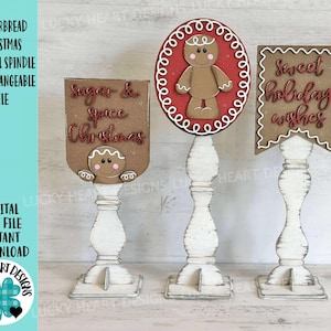 May include: Three white wooden pedestal spindles with interchangeable gingerbread-themed toppers. One topper reads "Sugar & Spice Christmas", another features a gingerbread man, and the third says "Sweet holiday wishes".