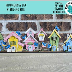 Può includere: Un set di sei casette per uccelli in legno colorate con uccelli azzurri appollaiati in cima. Le casette per uccelli sono disposte in fila su una base in legno. Le casette per uccelli sono dipinte in tonalità di rosa, giallo, verde e blu. Le casette per uccelli hanno diversi design, tra cui un cuore, una stella e un fiore. Le casette per uccelli sono un'ottima aggiunta a qualsiasi arredamento per la casa.