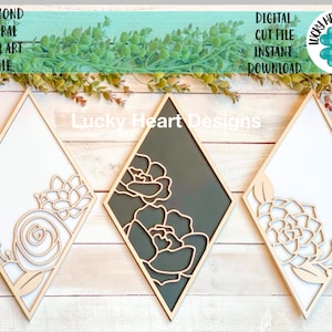 May include: Three diamond-shaped wall art pieces with floral designs. The frames are light wood, with white and dark gray backgrounds. The floral cutouts are in a natural wood tone. Text on the image reads "Diamond Floral Wall Art File" and "Digital Cut File Instant Download."