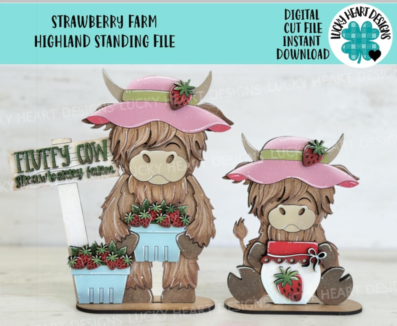 May include: Two Highland cow figurines, one larger than the other, both wearing pink hats with green leaves and red strawberries. The larger cow holds a basket of red strawberries and a sign that reads "Fluffy Cow Strawberry Farm".
