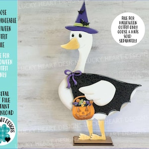 May include: A wooden goose cutout dressed for Halloween, with a witch's hat, cape, and a pumpkin bucket. The goose has a white body, yellow feet and beak. The hat is purple and black, and the cape is black with a bat-wing design. Text on the image says "Goose Interchangeable Halloween Outfit File".
