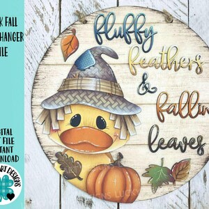 May include: A round wooden door hanger featuring a cartoon duck wearing a scarecrow hat, with the words "Fluffy Feathers & Falling Leaves." The duck is holding a leaf and a pumpkin. The words "Duck Fall Door Hanger File" are also visible.