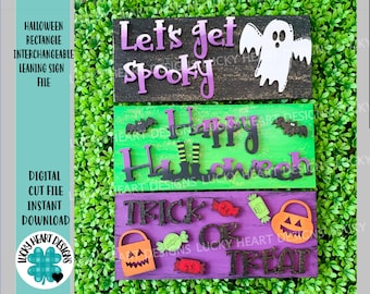 May include: Three interchangeable Halloween-themed wooden signs. The top sign is black with white ghost and purple text that reads "Let's get spooky". The middle sign is green with black witch's boots and black text that reads "Happy Halloween". The bottom sign is purple with orange jack-o-lantern and black text that reads "Trick or Treat".