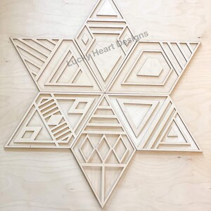 May include: A wooden geometric star wall decor with a variety of intricate patterns and designs. The star is made of multiple pieces that fit together to create a unique and modern look. The star is a light brown color and has a natural wood finish.