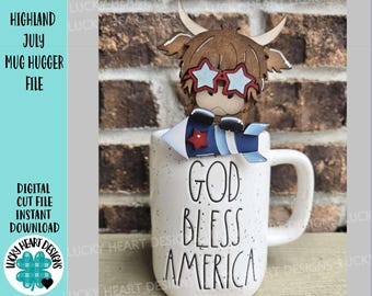 May include: A white mug with the words "GOD BLESS AMERICA" in black lettering. A brown Highland cow mug hugger with star-shaped glasses and a rocket is on top of the mug. The image also includes text that says "HIGHLAND JULY MUG HUGGER FILE".