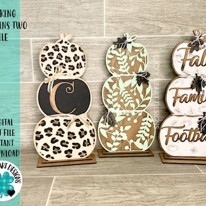 May include: Three wooden pumpkin-shaped signs with different designs. The top pumpkin says "Fall", the middle pumpkin says "Family", and the bottom pumpkin says "Football".