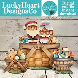 Könnte beinhalten: Eine digitale Schnittdatei mit einem großen Korb, der den Weihnachtsmann und Frau Weihnachtsmann enthält, flankiert von zwei kleineren Körben mit Lebkuchenmännern, einem Nudelholz, einem Weihnachtsstrumpf und verpackten Geschenken, mit dem Text LuckyHeartDesignsCo.