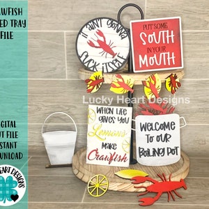 May include: A tiered tray with a crawfish theme. The top tier has a red sign that says "Put some South in your Mouth". The middle tier has a sign that says "When life gives you lemons make crawfish". The bottom tier has a sign that says "Welcome to our boiling pot".