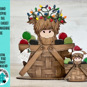 K&ouml;nnte beinhalten: Eine h&ouml;lzerne Weihnachtsdekoration mit einer Highland-Kuh, die einen Lichterkranz um den Kopf tr&auml;gt und in einem Korb mit Kugeln sitzt. Die Kuh tr&auml;gt einen roten Weihnachtsmann-Hut und h&auml;lt eine Glocke mit der Aufschrift "Cowbells don't you listen".