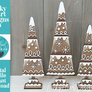 Può includere: Tre decorazioni per alberi di Natale in legno. Gli alberi sono marroni con accenti bianchi simili a glassa e dettagli di fiocchi di neve e punti. Gli alberi hanno una parte superiore bianca e poggiano su una base rettangolare.