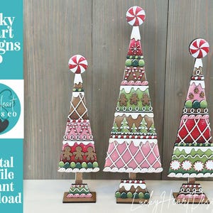 Könnte beinhalten: Drei Weihnachtsbaumdekorationen aus Holz mit Lebkuchen- und Zuckerstangenmotiven. Jeder Baum hat eine rot-weiße Pfefferminzstange oben. Die Bäume stehen auf einer Holzoberfläche. Der Text "Lucky Heart Designs Co" und "Digital cut file instant download" sind sichtbar.