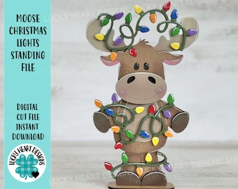 May include: A brown moose with a red nose and large eyes is decorated with a green garland of colorful Christmas lights. The moose is standing on a wooden base.