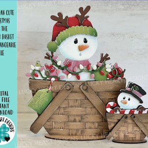 Könnte beinhalten: Ein hölzernes Weihnachtsdekorationsset mit Schneemännern. Der größere Korb zeigt einen Schneemann mit roter Mütze, Geweih und rosa Schal, umgeben von Lichterketten. Ein kleinerer Korb hat einen Schneemann mit Zylinder und Zuckerstange. Der Text auf dem Bild lautet "Snowman Cute Christmas".