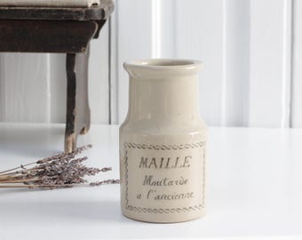 May include: A white ceramic jar with a brown lid and the text "MAILLE Mustard a l'ancienne" on the front.