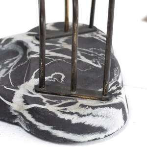 May include: Black and white marbled paperweight with a metal letter holder on top. The letter holder has three vertical bars.