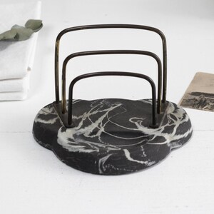 May include: A black and white marbled letter holder with a gold metal frame. The holder has three compartments for letters or papers.
