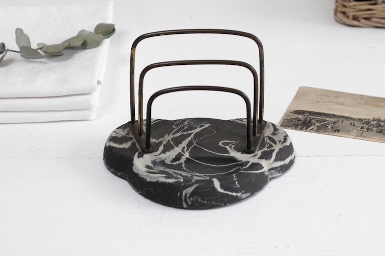 May include: A black and white marbled letter holder with a gold metal frame. The holder has three compartments for letters or papers.