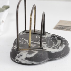 May include: A black and white marbled ceramic letter holder with a gold and black metal frame.
