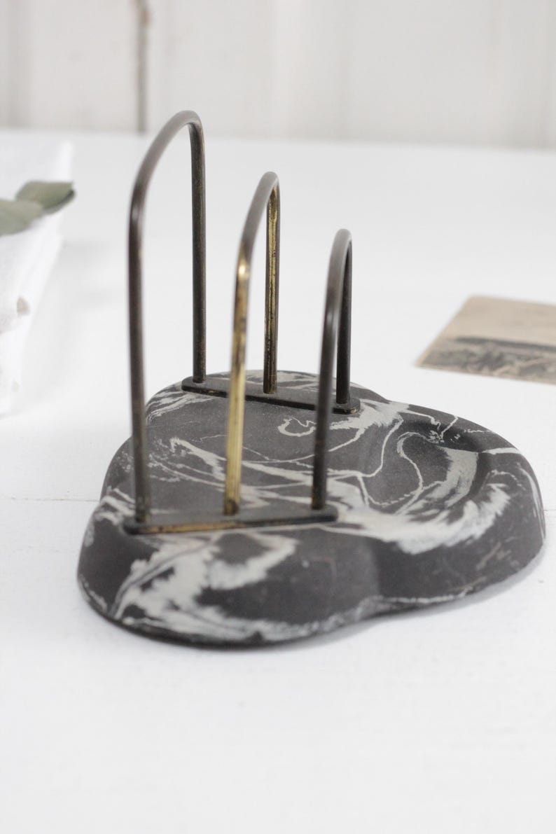 May include: A black and white marbled ceramic letter holder with a gold and black metal frame.