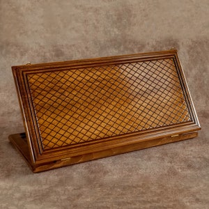 May include: A wooden laptop stand with a decorative diamond pattern carved into the top. The stand is closed and has a dark brown finish.