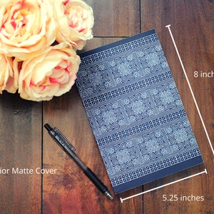 K&ouml;nnte beinhalten: Ein blaues Notizbuch mit einem wei&szlig;en geometrischen Muster auf dem Einband. Das Notizbuch misst 13,3 cm x 20,3 cm. "Exterior Matte Cover" steht in der linken unteren Ecke des Bildes.