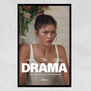 May include: A framed movie poster for "The Drama" featuring Zendaya and Robert Pattinson. The poster has a black frame and a distressed background. The title "The Drama" is in large white letters. The release date is April 3.