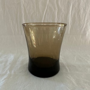 May include: A brown glass tumbler with a flared rim and a dark brown base.