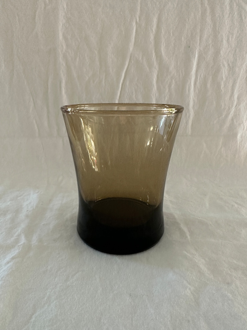 May include: A brown glass tumbler with a flared rim and a dark brown base.