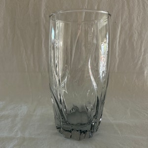May include: A clear glass drinking glass with a textured, wavy design. The glass has a wide base and a slightly flared top.