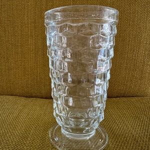 May include: A clear glass vase with a textured, diamond-shaped pattern. The vase has a wide base and a narrow opening.