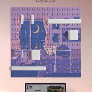 Può includere: Una lavagna forata viola con un'illustrazione di una scena notturna, con una luna crescente, uno skyline e due gatti bianchi. Include mensole e contenitori bianchi. Il logo "DESKNEKO" è in alto.