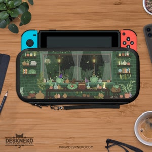 Op de afbeelding: Een Nintendo Switch-console rust in een zwarte hoes met een grillig kikker-thema-ontwerp. De hoes heeft een groene bakstenen muur, een raam met een regenachtige nachtscène en verschillende cartoonkikkers. De hoes heeft een zwarte polsband.