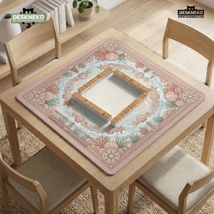 May include: A square, pink desk mat with a nautical design featuring seashells, starfish, and compass roses. A wooden frame sits in the center. The mat is on a wooden table with chairs. The brand name "DESKNEKO" is visible.