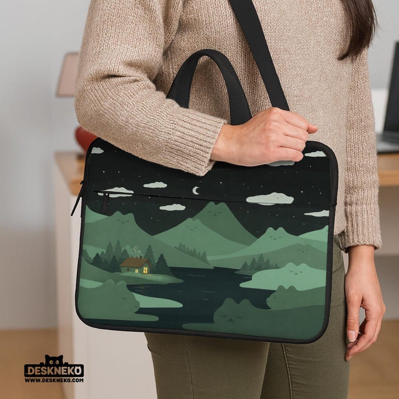 May include: A black laptop sleeve featuring a scenic landscape design with mountains, a river, and a cabin under a starry night sky. The sleeve has a black handle and shoulder strap. The brand name "DESKNEKO" is printed at the bottom.