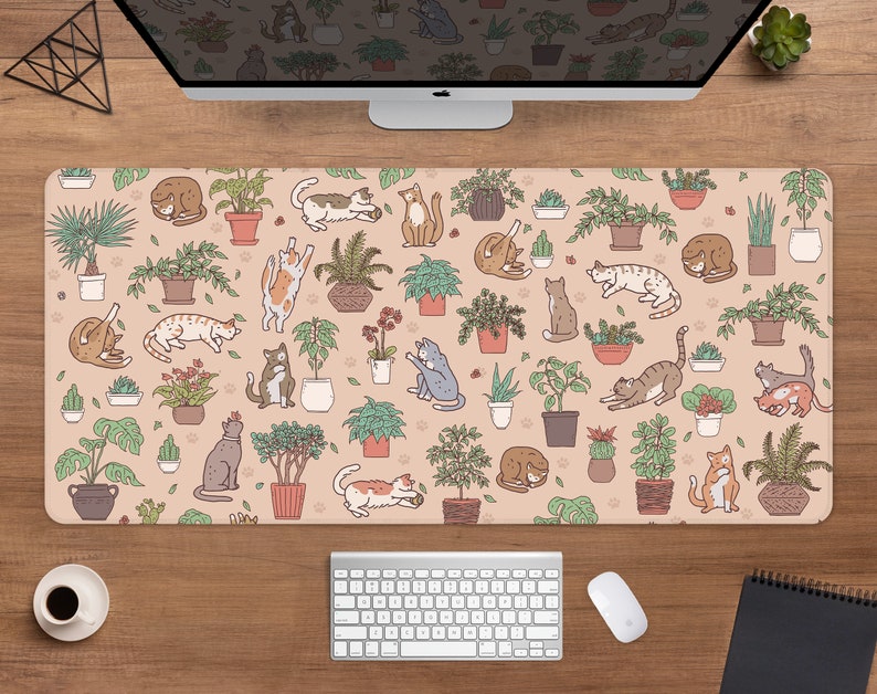 Puede incluir: Alfombrilla de escritorio rectangular con un patr&oacute;n repetido de gatos de dibujos animados y plantas en macetas sobre un fondo beige. Los gatos est&aacute;n en varias poses, y las plantas est&aacute;n en macetas marrones. Se ven una computadora, un teclado y un rat&oacute;n.