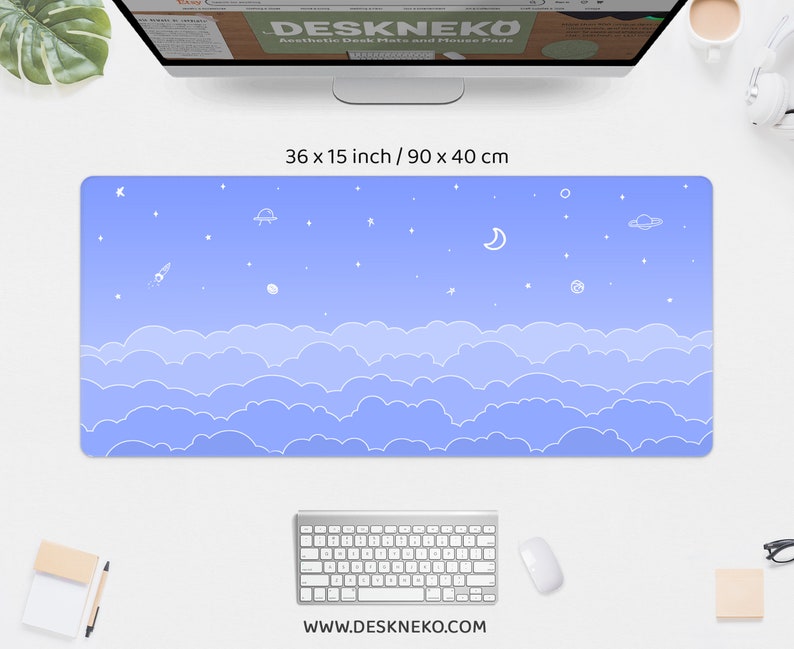 K&ouml;nnte beinhalten: Rechteckige Schreibtischunterlage mit Himmelsdesign. Die Matte ist 90 x 40 cm gro&szlig; und hat einen blauen Farbverlauf mit wei&szlig;en Wolken, Sternen, einem Mond und einer Rakete. Die Website-Adresse www.deskneko.com ist unten aufgedruckt.