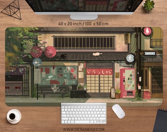 May include: A large rectangular mouse pad featuring an illustrated Japanese street scene with cats, umbrellas, and a vending machine. The pad measures 40 x 20 inches. The text "WWW.DESKNEKO.COM" is printed at the bottom.