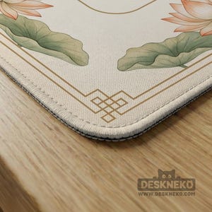 May include: A beige desk mat featuring a floral design with lotus flowers and leaves in shades of pink and green. The mat has a geometric border and the text "DESKNEKO" and "WWW.DESKNEKO.COM" in the bottom right corner.
