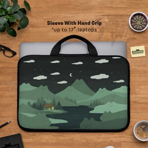 May include: Black laptop sleeve with a hand grip, featuring a landscape design of mountains, a lake, and a house under a starry night sky. The sleeve is designed for laptops up to 17 inches.