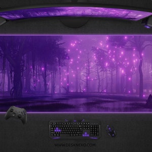 May include: A large, rectangular purple mouse pad with a forest scene, a curved monitor, and gaming accessories. The mouse pad features a mystical forest with glowing lights. A keyboard, mouse, controller, and headset are also visible.