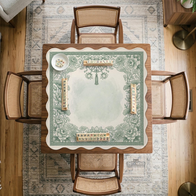 May include: Overhead view of a wooden square Mahjong table with four rattan chairs. The table has a green and white floral patterned mat with Mahjong tiles and a small bowl. The table is set on a patterned rug and hardwood floor.