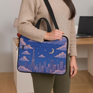 May include: A laptop bag with a nighttime cityscape design, featuring a crescent moon, stars, and clouds. The bag has a black shoulder strap and a handle. The color scheme includes blue, pink, and white hues.