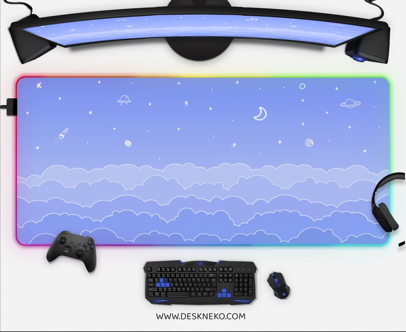 K&ouml;nnte beinhalten: Gro&szlig;es rechteckiges Gaming-Mauspad mit einem Himmelsdesign mit Wolken, Sternen, einer Rakete und einem UFO. Das Pad hat einen farbverlaufenden Rand mit einem Regenbogen von Farben. Eine Tastatur, eine Maus und ein Gamecontroller sind sichtbar.